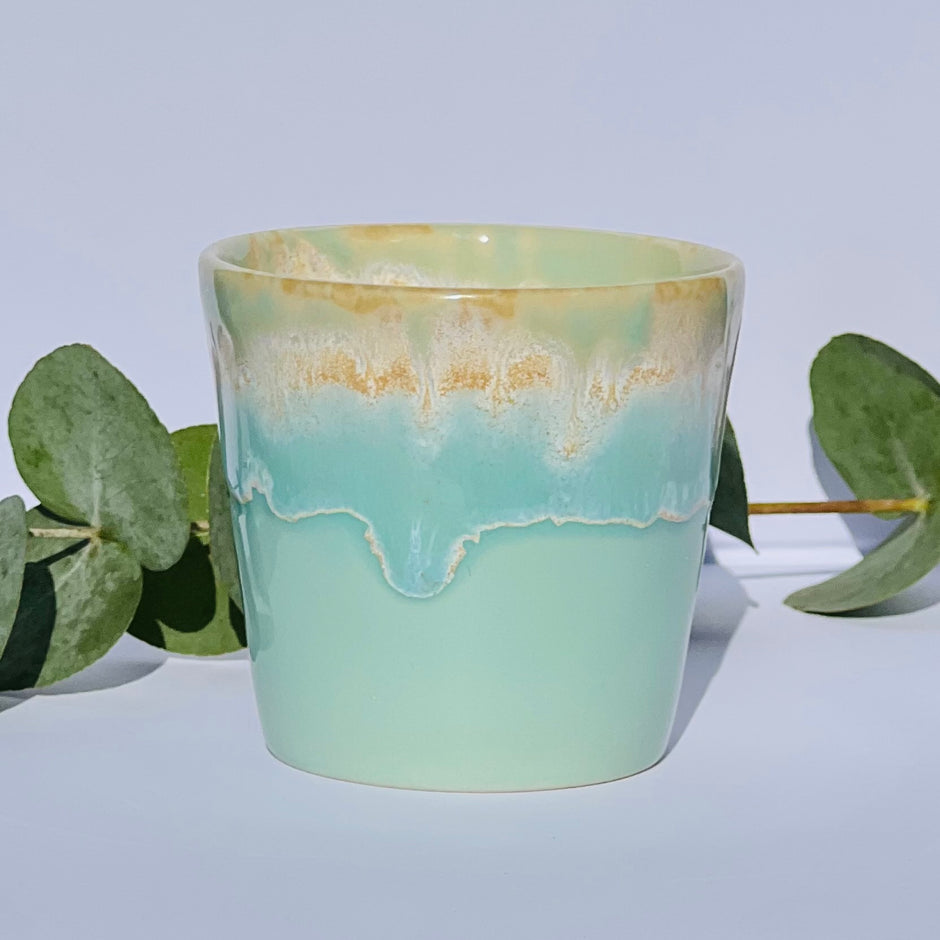 Aromatherapy candle in an aqua-glazed stoneware coffee cup, made with natural wax and essential oils. Handmade by Kilimanjaro Candles & More, supporting young schoolgirls in Kenya.
