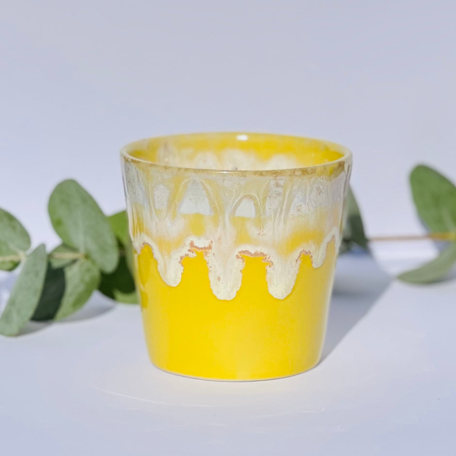 Aromatherapy candle in a yellow-glazed stoneware coffee cup, filled with natural wax and essential oils. Handmade by Kilimanjaro Candles & More, supporting young schoolgirls in Kenya.