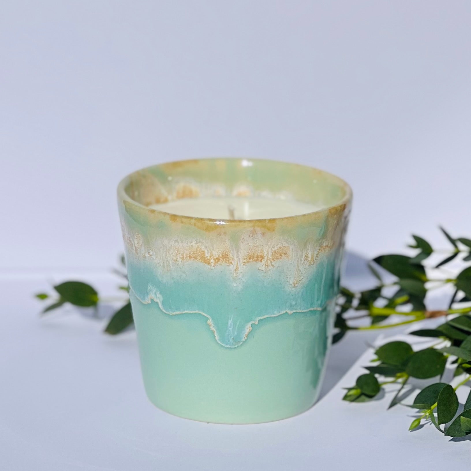 Aromatherapy candle in an aqua-glazed stoneware coffee cup, made with natural wax and essential oils. Handmade by Kilimanjaro Candles & More, supporting young schoolgirls in Kenya.
