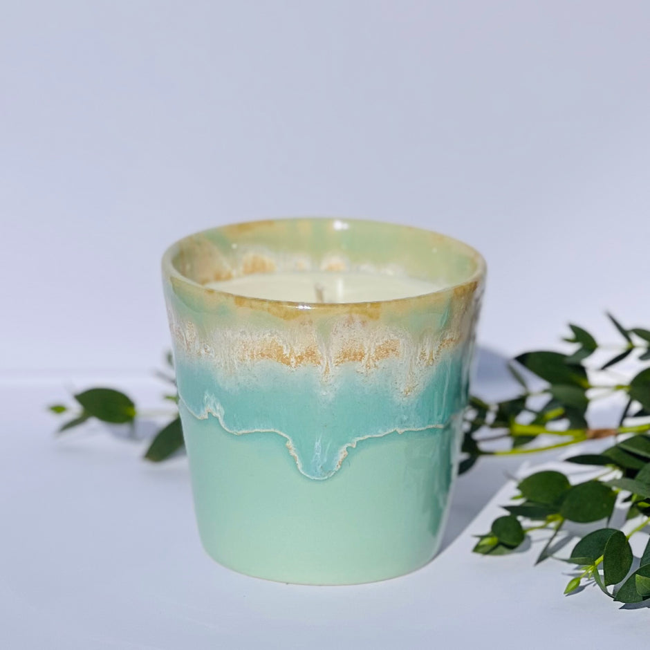 Aromatherapy candle in an aqua-glazed stoneware coffee cup, made with natural wax and essential oils. Handmade by Kilimanjaro Candles & More, supporting young schoolgirls in Kenya.